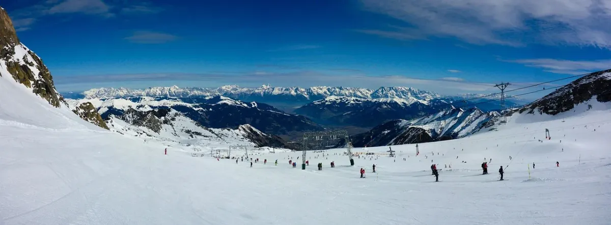 Narciarz zjeżdżający po zaśnieżonym stoku w ośrodku Kitzsteinhorn na tle malowniczej panoramy gór.